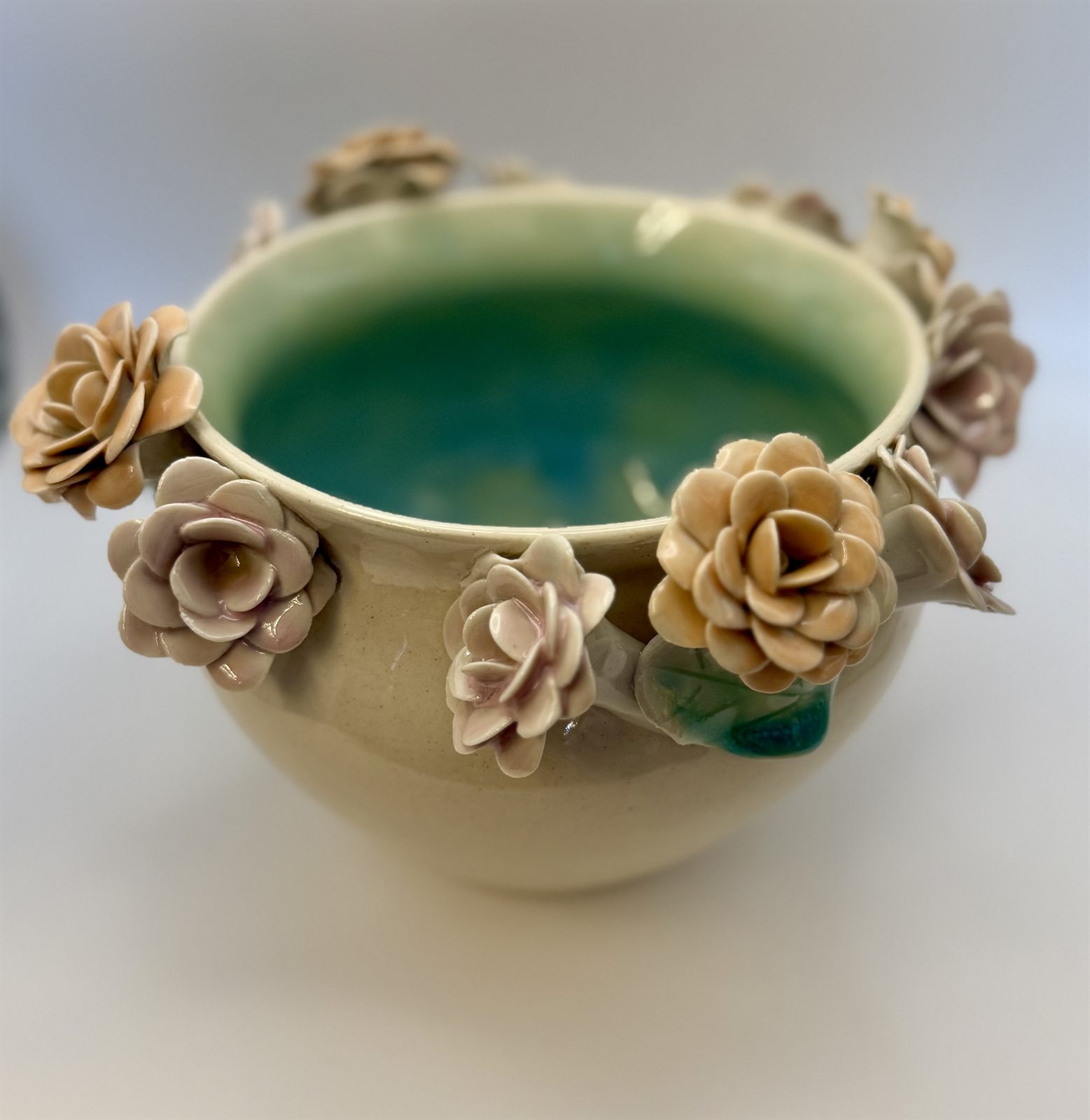 Cream bowl with blush and amber blooms and a deep teal interior